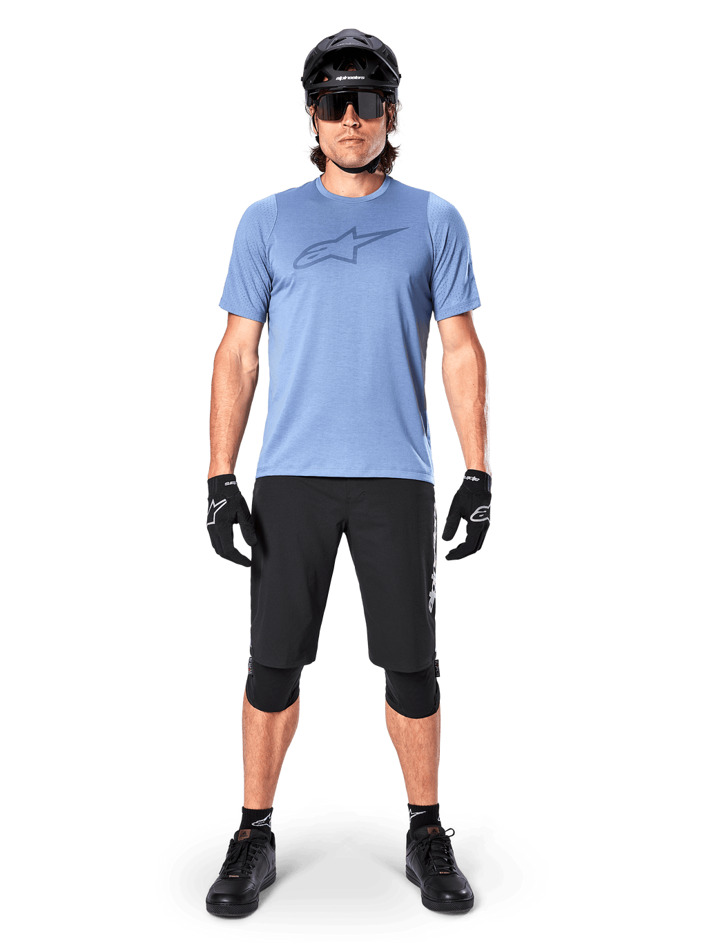 Alpinestars Pantaloncini A-Dura Elite, pantaloncini da mountain bike neri, indossati con una t-shirt azzurra, casco nero, occhiali da sole e ginocchiere, abbigliamento professionale per ciclismo fuoristrada