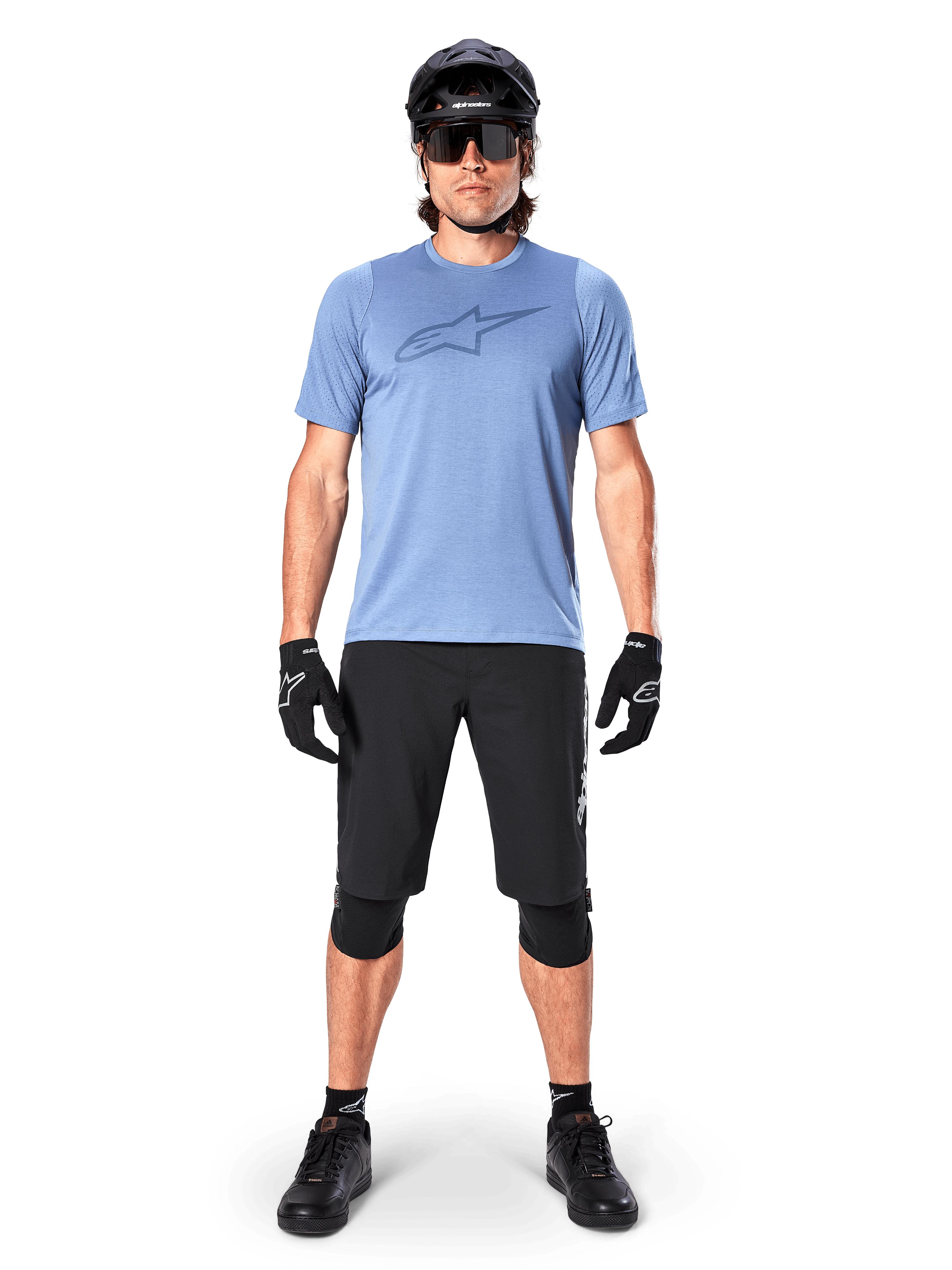 Alpinestars Pantaloncini A-Dura Elite, pantaloncini da mountain bike neri, indossati con una t-shirt azzurra, casco nero, occhiali da sole e ginocchiere, abbigliamento professionale per ciclismo fuoristrada