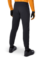 Alpinestars A-Dura Pants, pantaloni MTB neri, vista posteriore, indossati con una maglia a maniche lunghe arancione e guanti neri, con polsini elasticizzati e materiale tessile resistente per la mountain bike.