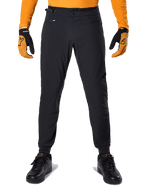 Pantaloni Alpinestars A-Dura, pantaloni da mountain bike, nero, indossati con una maglia arancione a maniche lunghe e guanti neri e arancioni, caratterizzati da una doppia chiusura a scatto e regolatori laterali in vita, in tessuto resistente per il ciclismo fuoristrada