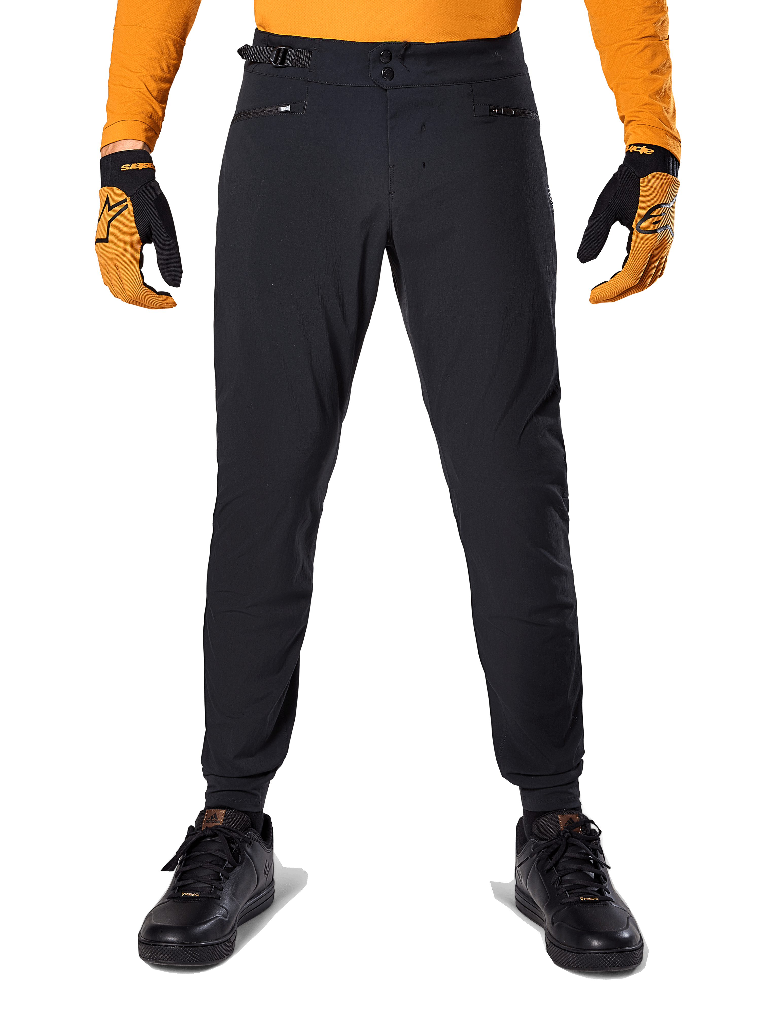 Pantaloni Alpinestars A-Dura, pantaloni da mountain bike, nero, indossati con una maglia arancione a maniche lunghe e guanti neri e arancioni, caratterizzati da una doppia chiusura a scatto e regolatori laterali in vita, in tessuto resistente per il ciclismo fuoristrada
