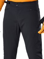 Alpinestars A-Dura Pants, pantaloni da ciclismo MTB neri, vista ravvicinata con doppia chiusura a scatto in vita, regolatore laterale della vita e tasche con cerniera, abbinati a maglia e guanti arancioni