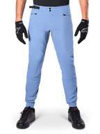 Alpinestars Pantaloni A-Dura, pantaloni MTB, Infinity Blue, pantaloni da mountain bike azzurri con doppia chiusura a scatto e tasche con cerniera, indossati con guanti neri e scarpe nere, vestibilità regolare con polsini elasticizzati