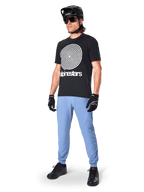 Pantaloni Alpinestars A-Dura, pantaloni da MTB, Infinity Blue, indossati con t-shirt grafica nera con logo a spirale bianco, casco nero, occhiali da sole e guanti neri, abbigliamento professionale da mountain bike