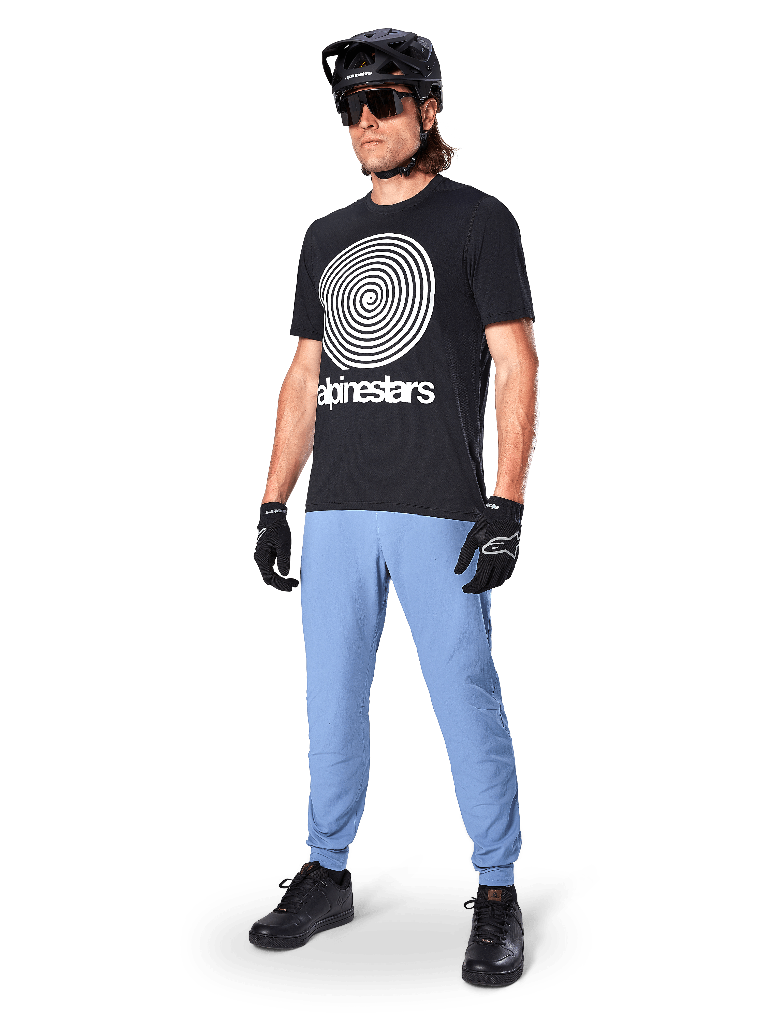 Pantaloni Alpinestars A-Dura, pantaloni da MTB, Infinity Blue, indossati con t-shirt grafica nera con logo a spirale bianco, casco nero, occhiali da sole e guanti neri, abbigliamento professionale da mountain bike