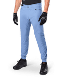 Alpinestars A-Dura Pants, pantaloni da ciclismo MTB Infinity Blue, con doppia chiusura frontale a scatto e tasche con cerniera, indossati con guanti neri e scarpe nere, tessuto resistente elasticizzato in 2 direzioni per la guida fuoristrada
