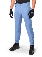 Alpinestars A-Dura Pants, pantaloni da ciclismo MTB Infinity Blue, con doppia chiusura frontale a scatto e tasche con cerniera, indossati con guanti neri e scarpe nere, tessuto resistente elasticizzato in 2 direzioni per la guida fuoristrada