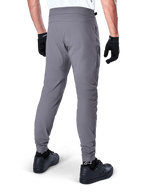 Alpinestars A-Dura Pants, pantaloni da mountain bike, grigio scuro, vista posteriore del modello che indossa l'attrezzatura, con un resistente tessuto elasticizzato in 2 direzioni e polsini elasticizzati, abbinati a guanti e sneaker neri per un look pronto per il ciclismo
