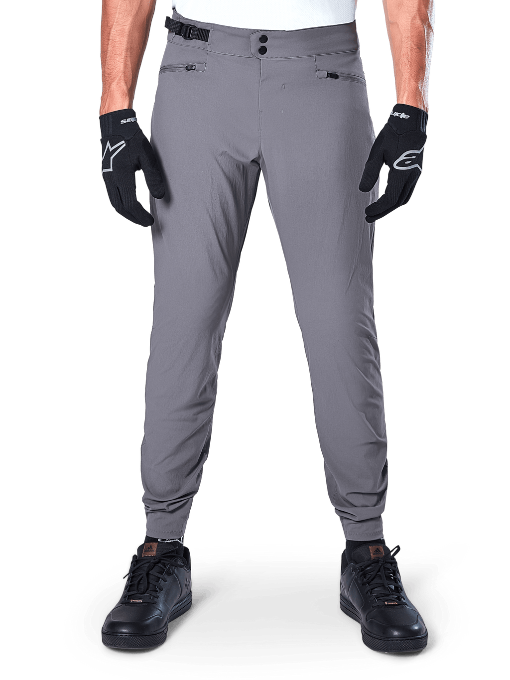 Pantaloni Alpinestars A-Dura, pantaloni da mountain bike grigio scuro, vista frontale indossati con guanti e sneaker neri, con doppia chiusura a scatto in vita, tasche con zip e polsini elasticizzati, abbigliamento da ciclismo resistente per trail riding