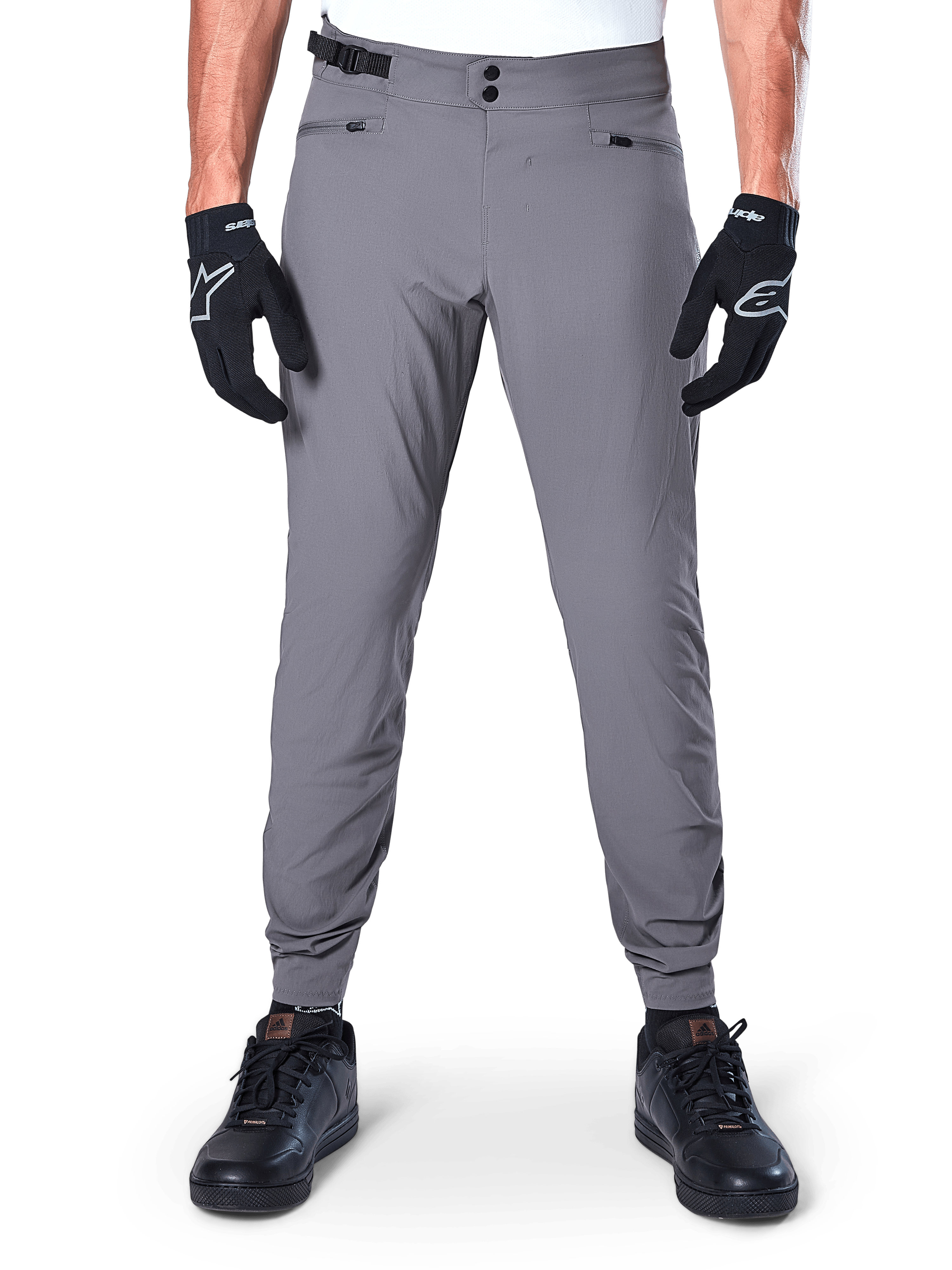 Pantaloni Alpinestars A-Dura, pantaloni da mountain bike grigio scuro, vista frontale indossati con guanti e sneaker neri, con doppia chiusura a scatto in vita, tasche con zip e polsini elasticizzati, abbigliamento da ciclismo resistente per trail riding