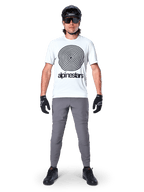 Pantaloni Alpinestars A-Dura, pantaloni da ciclismo MTB, grigio scuro, indossati con una t-shirt grafica bianca, casco nero e guanti, caratterizzati da un design resistente elasticizzato in 2 direzioni e vestibilità regolare per mountain bike