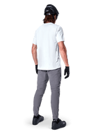 Pantaloni Alpinestars A-Dura, pantaloni da mountain bike grigio scuro visti dal retro, indossati con t-shirt bianca a maniche corte, casco da MTB nero, guanti e scarpe neri, design regular fit con polsini elasticizzati, abbigliamento resistente per ciclismo fuoristrada