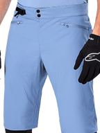 Pantaloncini Alpinestars A-Dura, shorts da mountain bike in Infinity Blue, primo piano della vita con chiusura a doppio scatto, regolazione laterale e tasche con zip foderate in rete, indossati con un guanto Alpinestars nero