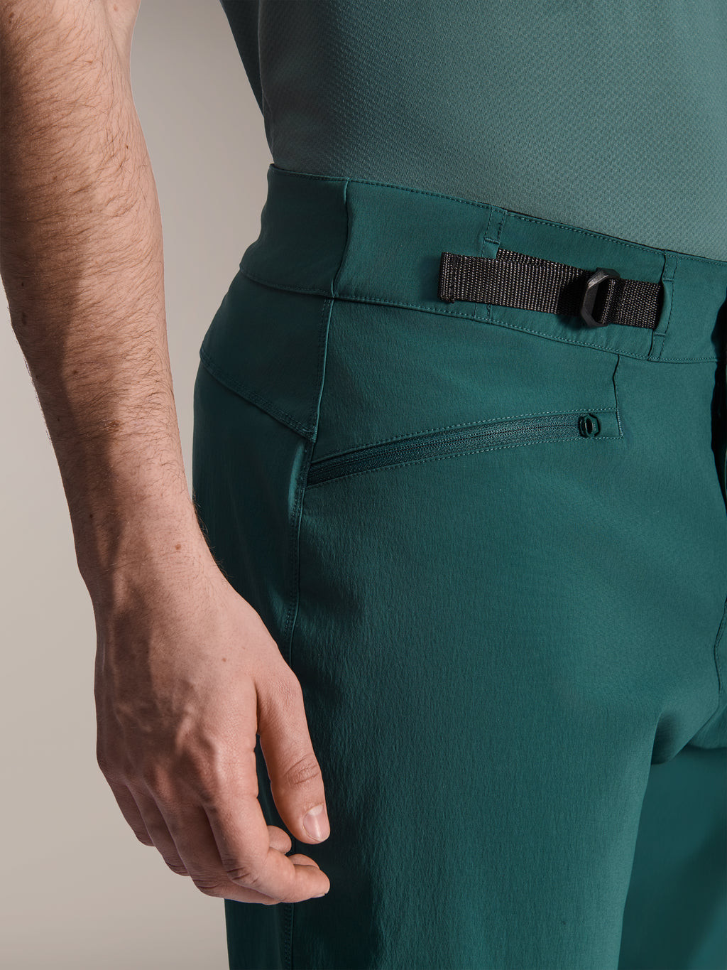 Alpinestars A-Dura Shorts, verde Dark Pine, vista ravvicinata del cinturino di regolazione laterale della vita e della tasca con zip, abbigliamento tecnico resistente per mountain bike.