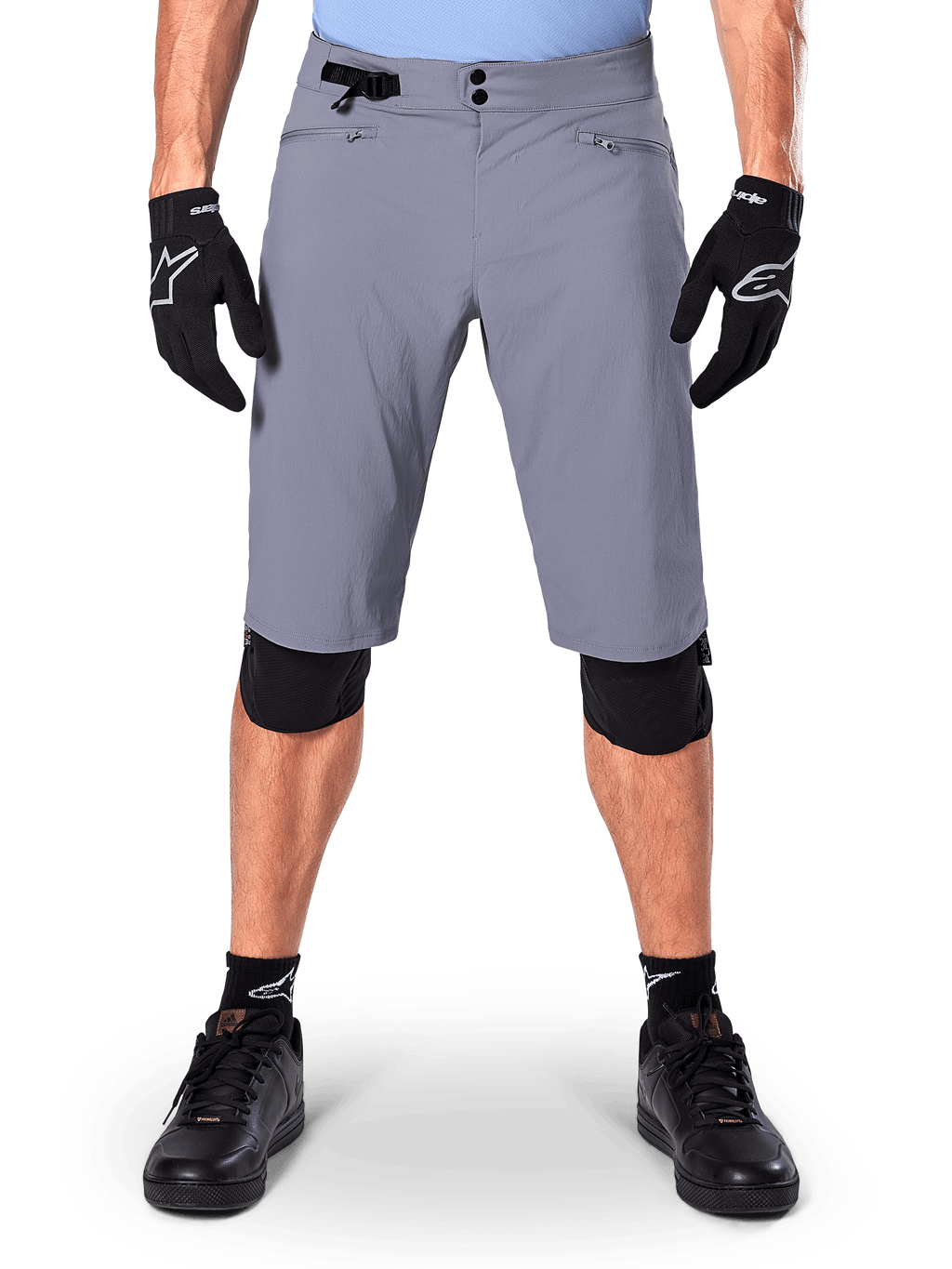 Alpinestars A-Dura Shorts, pantaloncini da mountain bike, grigio scuro, indossati con guanti e ginocchiere Alpinestars neri, caratterizzati da chiusura a doppio scatto e tasche foderate in rete con zip, tessuto resistente elasticizzato in 2 direzioni per il ciclismo fuoristrada