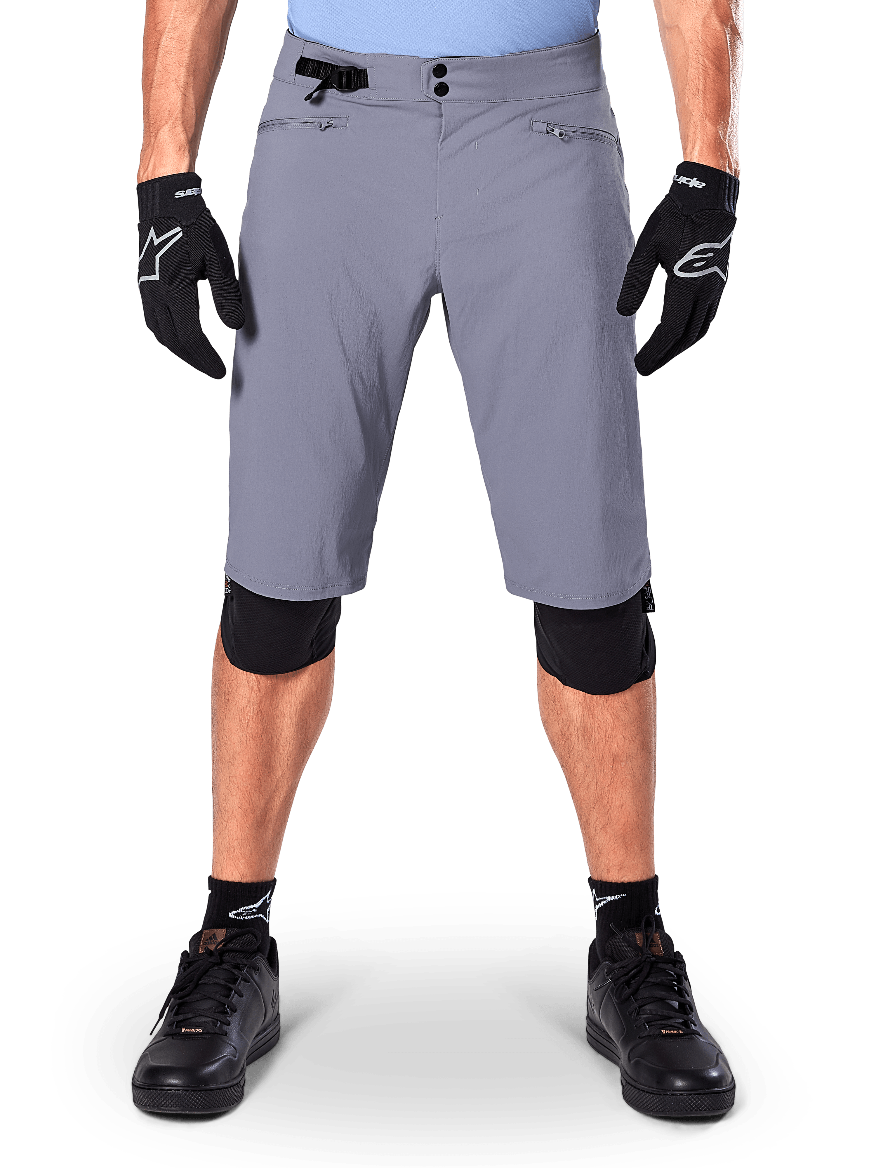 Alpinestars A-Dura Shorts, pantaloncini da mountain bike, grigio scuro, indossati con guanti e ginocchiere Alpinestars neri, caratterizzati da chiusura a doppio scatto e tasche foderate in rete con zip, tessuto resistente elasticizzato in 2 direzioni per il ciclismo fuoristrada