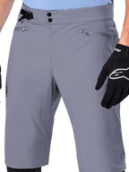 Alpinestars Shorts A-Dura, pantaloncini da MTB, grigio scuro, vista ravvicinata della vita con chiusura a doppio scatto, regolatore laterale e tasche con zip, abbinati a guanti da ciclismo neri, abbigliamento resistente da mountain bike