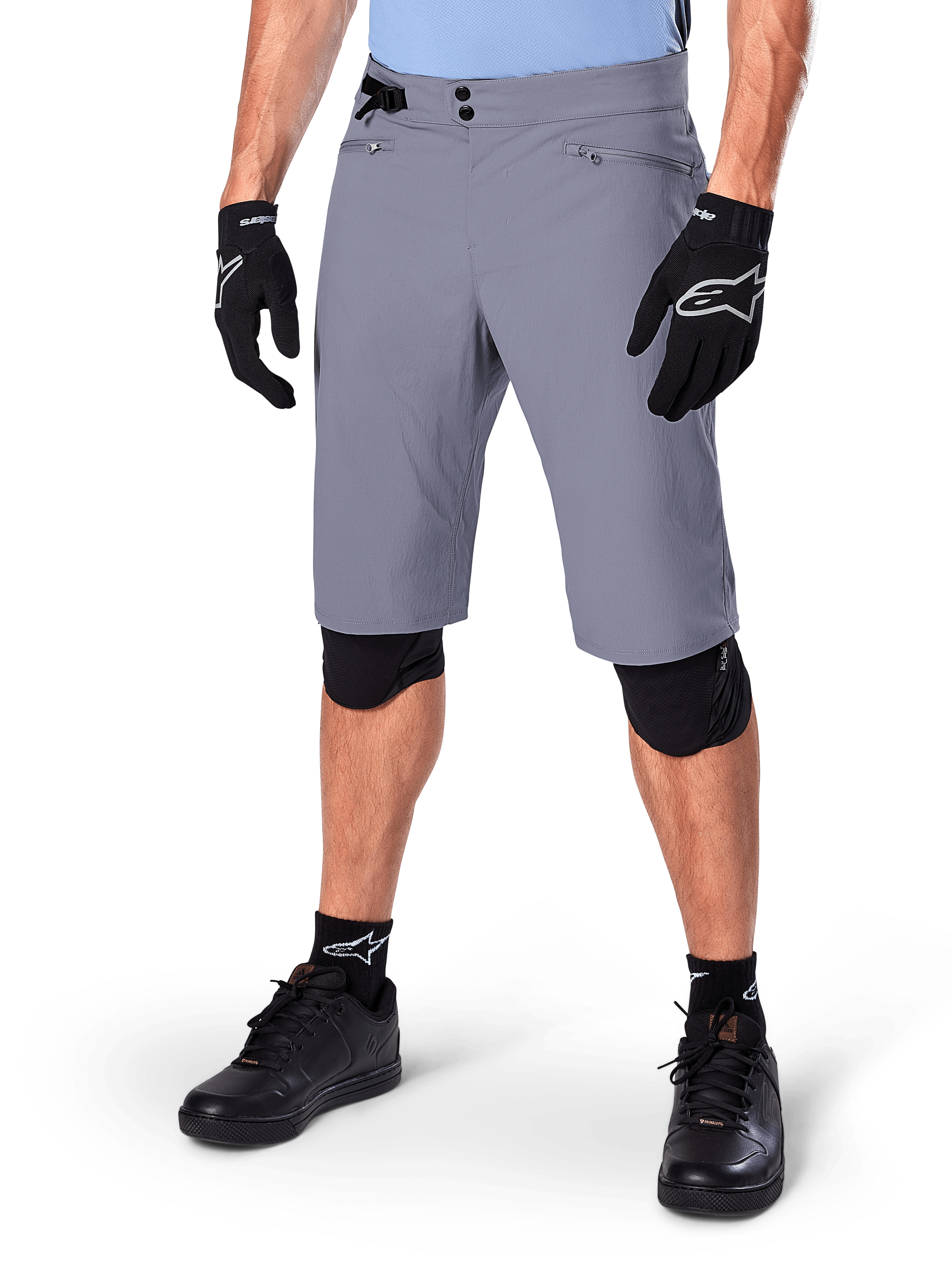 Alpinestars Shorts A-Dura, pantaloncini da mountain bike grigio scuro, abbinati a guanti e ginocchiere neri, con tasche con zip e chiusura a doppio scatto, abbigliamento robusto da ciclismo per percorsi off-road