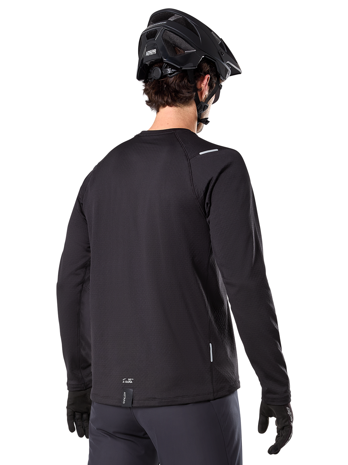 Alpinestars A-Dura Thermal Jersey, maglia da mountain bike a maniche lunghe, nero, vista posteriore con coda allungata, piccoli dettagli riflettenti e logo sull'orlo, indossata con casco e guanti neri per il ciclismo in climi freddi