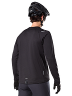 Alpinestars A-Dura Thermal Jersey, maglia da mountain bike a maniche lunghe, nero, vista posteriore con coda allungata, piccoli dettagli riflettenti e logo sull'orlo, indossata con casco e guanti neri per il ciclismo in climi freddi