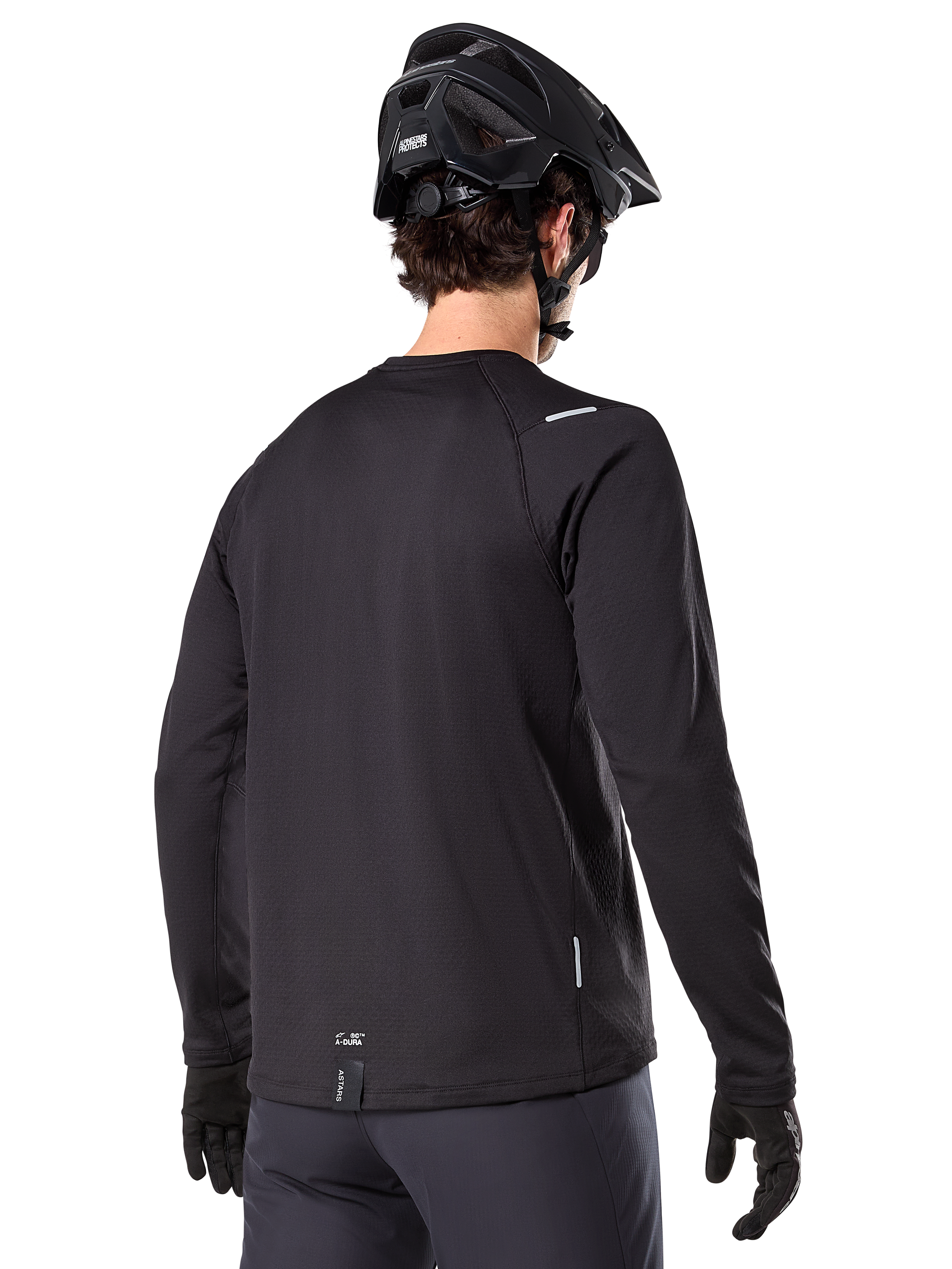 Alpinestars A-Dura Thermal Jersey, maglia da mountain bike a maniche lunghe, nero, vista posteriore con coda allungata, piccoli dettagli riflettenti e logo sull'orlo, indossata con casco e guanti neri per il ciclismo in climi freddi