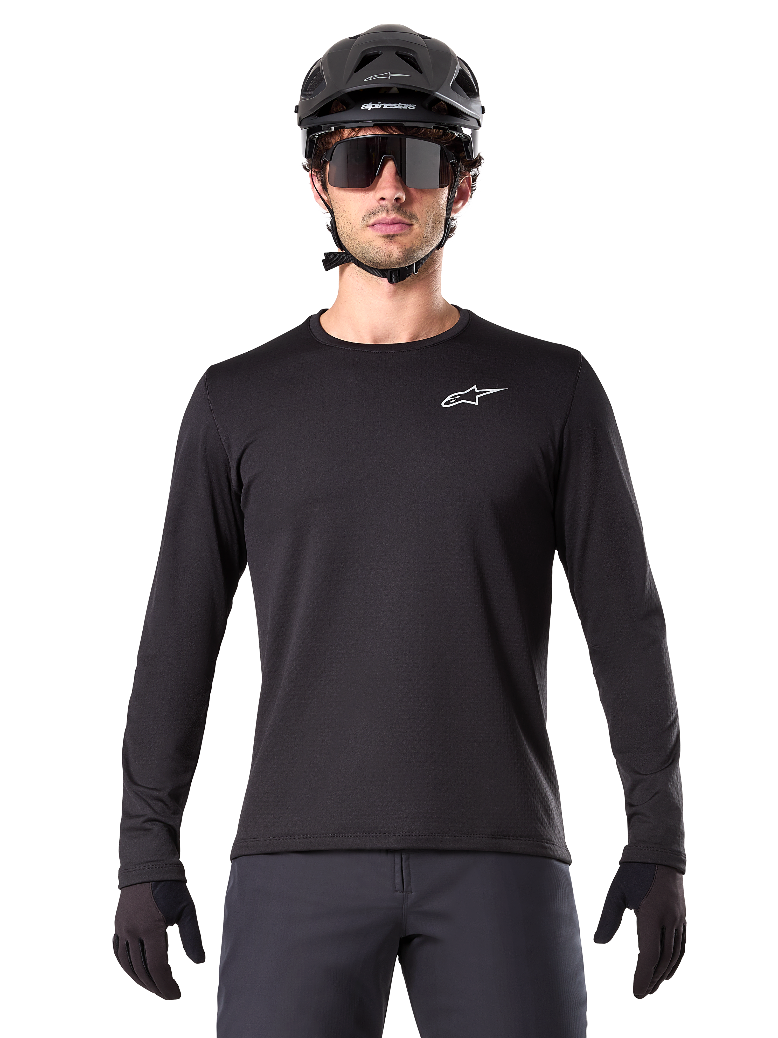 Alpinestars A-Dura Thermal Jersey, maglia da mountain bike a maniche lunghe nera, indossata con casco nero e grandi occhiali da sole, con un piccolo logo Alpinestars bianco sul petto, vestibilità regolare, abbigliamento da ciclismo MTB