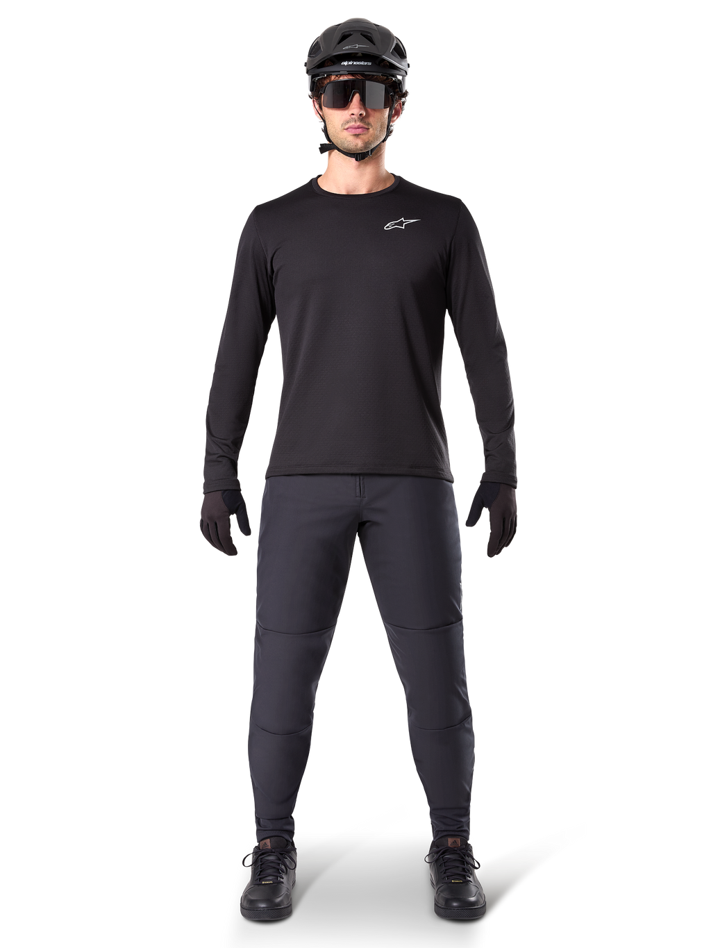 Alpinestars A-Dura Thermal Jersey, maglia da mountain bike a maniche lunghe nera, indossata con pantaloni grigio scuro, guanti neri, casco nero e occhiali da sole, con logo Alpinestars bianco sul petto, outfit coordinato per il mountain biking in climi freddi