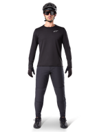 Alpinestars A-Dura Thermal Jersey, maglia da mountain bike a maniche lunghe nera, indossata con pantaloni grigio scuro, guanti neri, casco nero e occhiali da sole, con logo Alpinestars bianco sul petto, outfit coordinato per il mountain biking in climi freddi