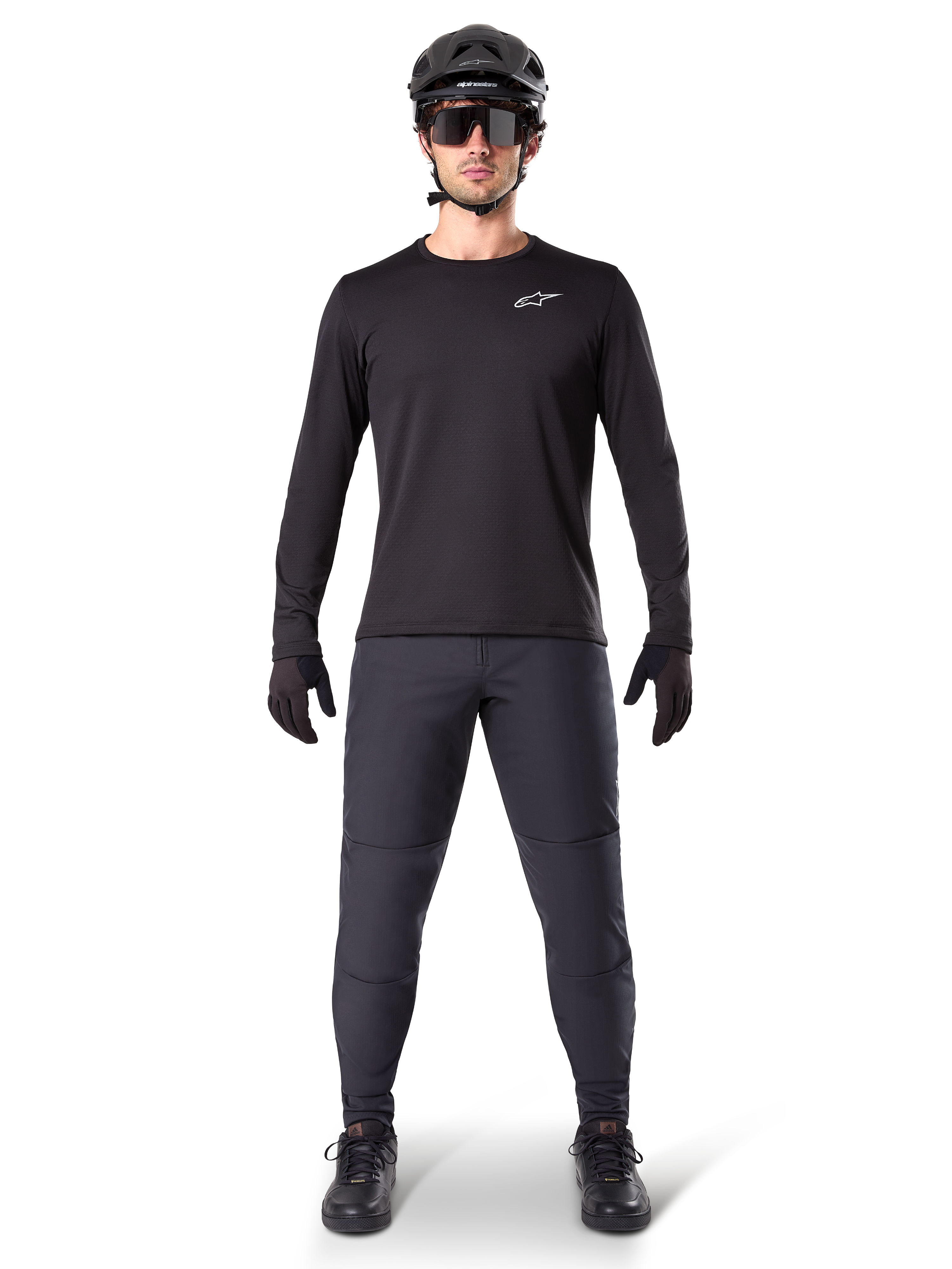 Alpinestars A-Dura Thermal Jersey, maglia da mountain bike a maniche lunghe nera, indossata con pantaloni grigio scuro, guanti neri, casco nero e occhiali da sole, con logo Alpinestars bianco sul petto, outfit coordinato per il mountain biking in climi freddi
