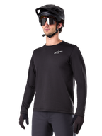 Alpinestars A-Dura Thermal Jersey, maglia da mountain bike a maniche lunghe nera, logo bianco sul petto, indossata con casco e guanti neri, design sportivo e lineare per trail riding
