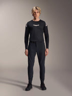 Modello che indossa la maglia a maniche lunghe Alpinestars A-Aria Polartec Elite in nero, con logo Astars bianco sul petto e branding sulle spalle, abbinata a pantaloni tecnici da MTB e scarpe neri, abbigliamento professionale per mountain bike