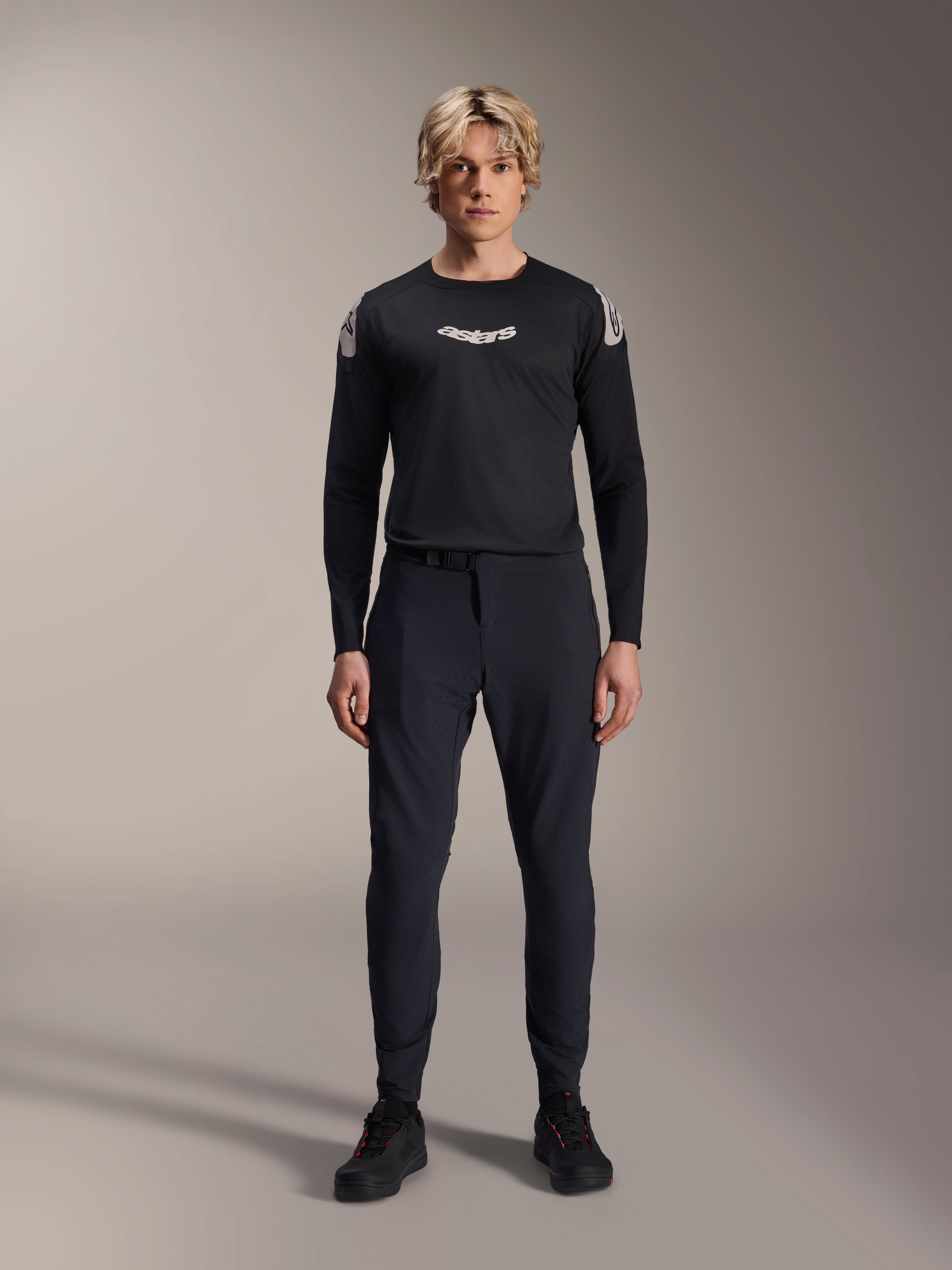 Alpinestars A-Aria Elite Pants, pantaloni da MTB Black Titanium, indossati da un modello con maglia a maniche lunghe coordinata e sneakers, design slim-fit performante con chiusura a fibbia magnetica, abbigliamento tecnico da mountain bike