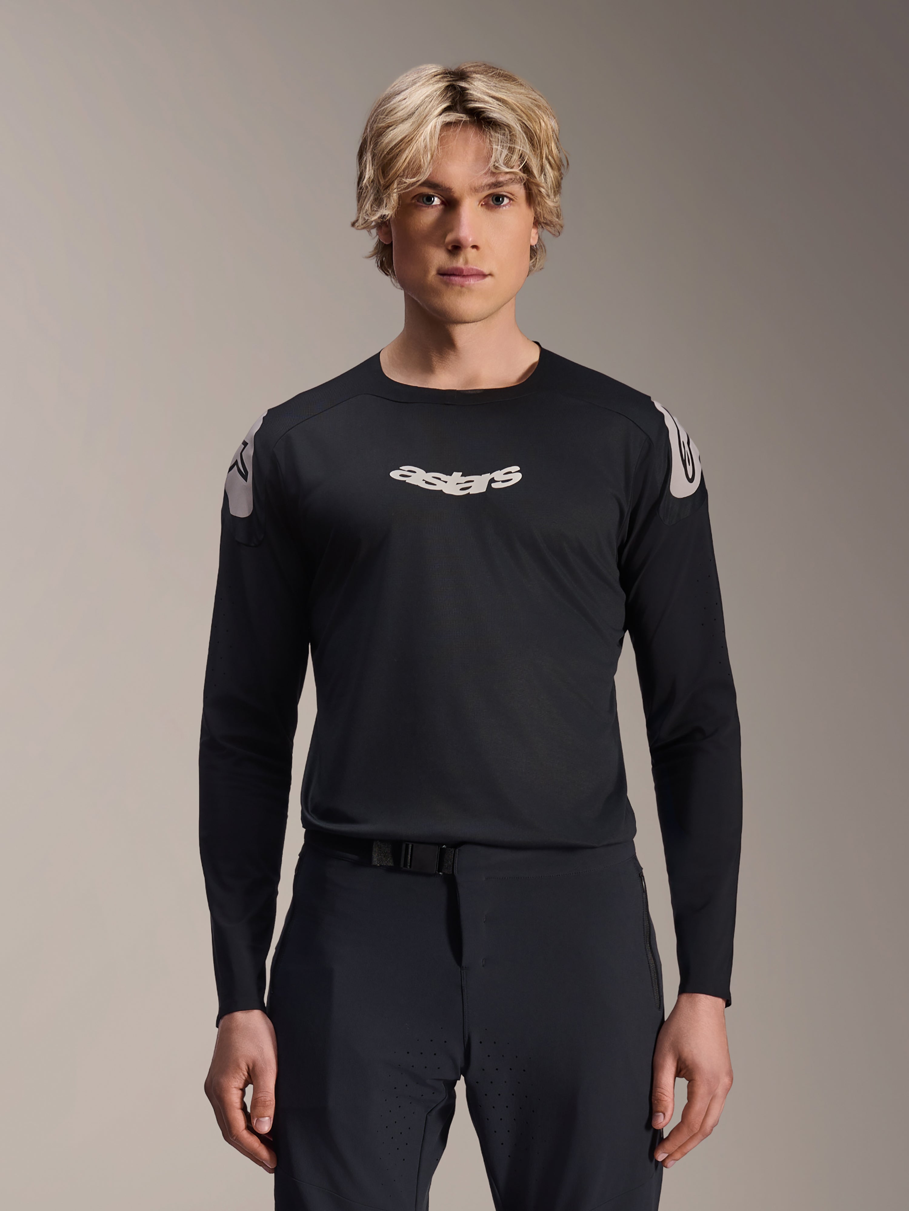 Alpinestars A-Aria Polartec Elite Jersey, maglia MTB a maniche lunghe, nera, con logo 'astars' bianco sul petto e grafiche bianche sulle spalle, abbigliamento tecnico da ciclismo indossato da un modello
