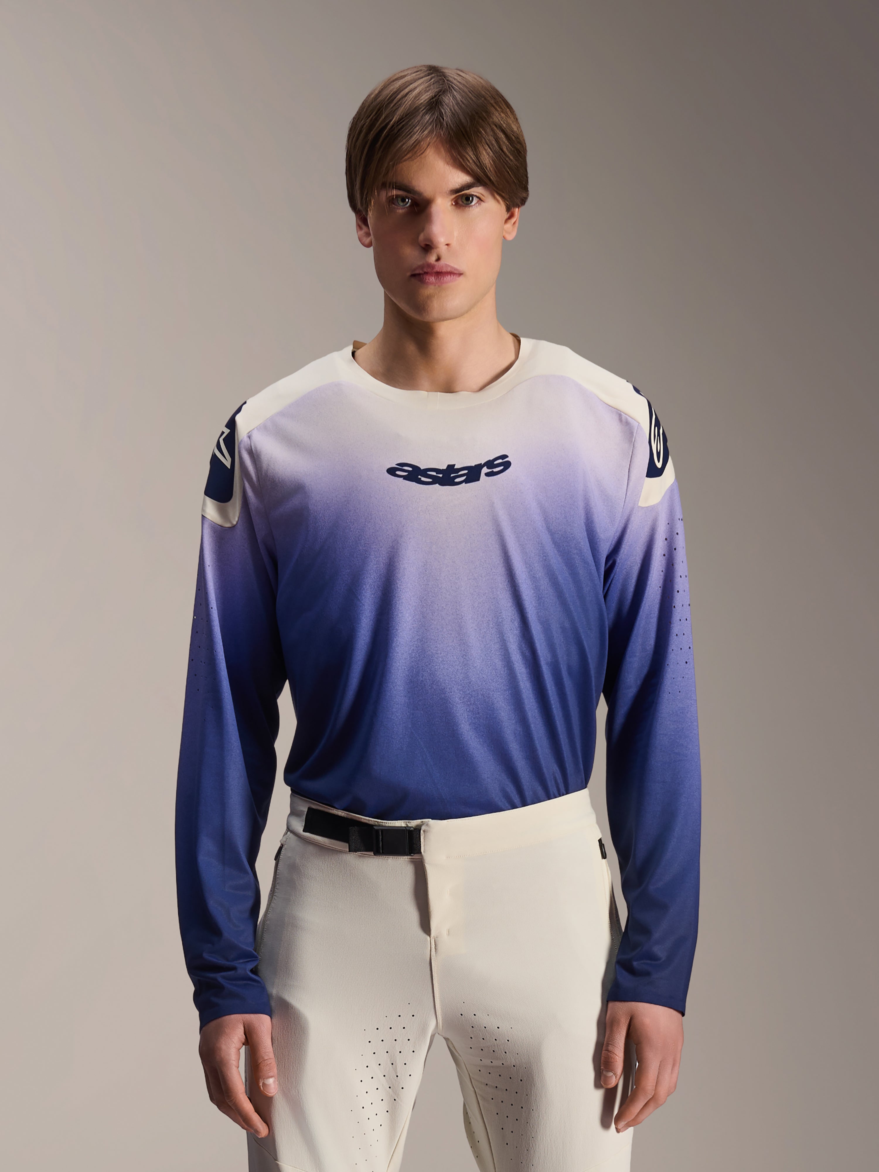 Alpinestars A-Aria Polartec Maker Elite Jersey, maglia MTB a maniche lunghe, Baja Blue con gradiente da bianco a blu, indossata da un modello con pantaloni bianchi, con logo blu scuro sul petto e perforazioni laser sulle maniche, abbigliamento tecnico da mountain bike
