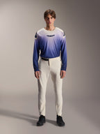 Alpinestars A-Aria Elite Pants, pantaloni da MTB performance in colore Ecru, pantaloni da ciclismo bianco panna con pannelli sulle cosce traforati al laser e fibbia magnetica, indossati con maglia a maniche lunghe blu sfumata e scarpe nere, vestibilità tecnica per trail riding