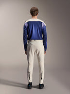 Alpinestars A-Aria Polartec Maker Elite Long Sleeve Jersey, Baja Blue e bianco sporco, vista posteriore del modello che indossa abbigliamento tecnico da mountain bike, inclusi pantaloni bianco sporco con marchio Alpinestars sulla parte inferiore delle gambe, completo da ciclismo per percorsi off-road