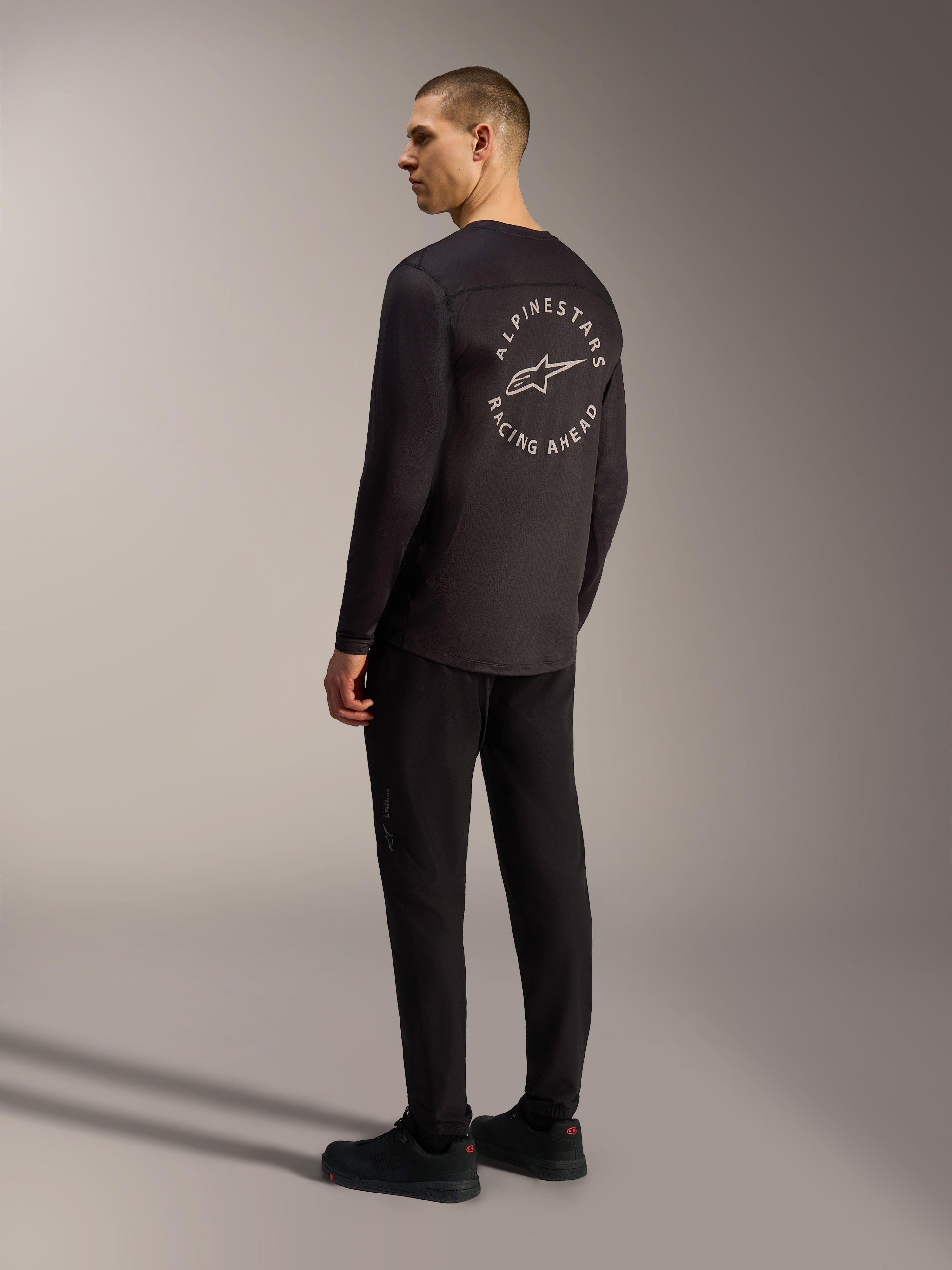 Alpinestars A-Dura Air, maglia nera a maniche lunghe con grafica circolare Racing Ahead sul retro, stile MTB.