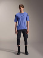 Alpinestars A-Aria Lite Short, pantaloncini MTB da uomo, nero, indossati con maglia a maniche corte viola chiaro e ginocchiere nere, abbigliamento MTB performante