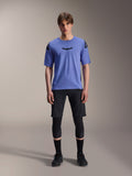 Alpinestars A-Aria Elite Shorts, pantaloncini da mountain bike MTB, Nero Titanium, indossati con maglia blu a maniche corte, protezioni per le ginocchia e scarpe da ciclismo nere, scatto in studio a figura intera, abbigliamento tecnico per mountain bike