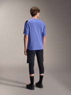 Maglia a maniche corte Alpinestars A-Aria Polartec Elite in Baja Blue, vista posteriore su un modello maschile, abbinata a pantaloncini MTB neri e protezioni per le ginocchia, vestibilità performante e orlo posteriore allungato per trail riding.