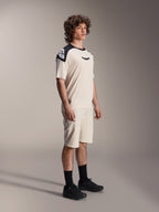 Alpinestars A-Aria Polartec Elite Short Sleeve Jersey, color ecru con pannelli sulle spalle e logo neri, indossata da un modello con pantaloncini coordinati e scarpe nere, abbigliamento tecnico da mountain bike per il trail riding fuoristrada.