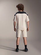 Pantaloncini Alpinestars A-Aria Elite e maglia A-Aria Polartec Elite SS, colore Ecru con pannelli neri sulle spalle, vista posteriore di un modello con abbigliamento tecnico da mountain bike, abbinato a calze e scarpe nere
