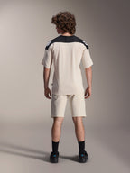 Maglia a maniche corte Alpinestars A-Aria Polartec Elite, maglia da ciclismo MTB, color ecru con pannelli sulle spalle neri, vista posteriore con pantaloncini coordinati e calze nere, vestibilità performante con design a coda allungata per la guida fuoristrada.
