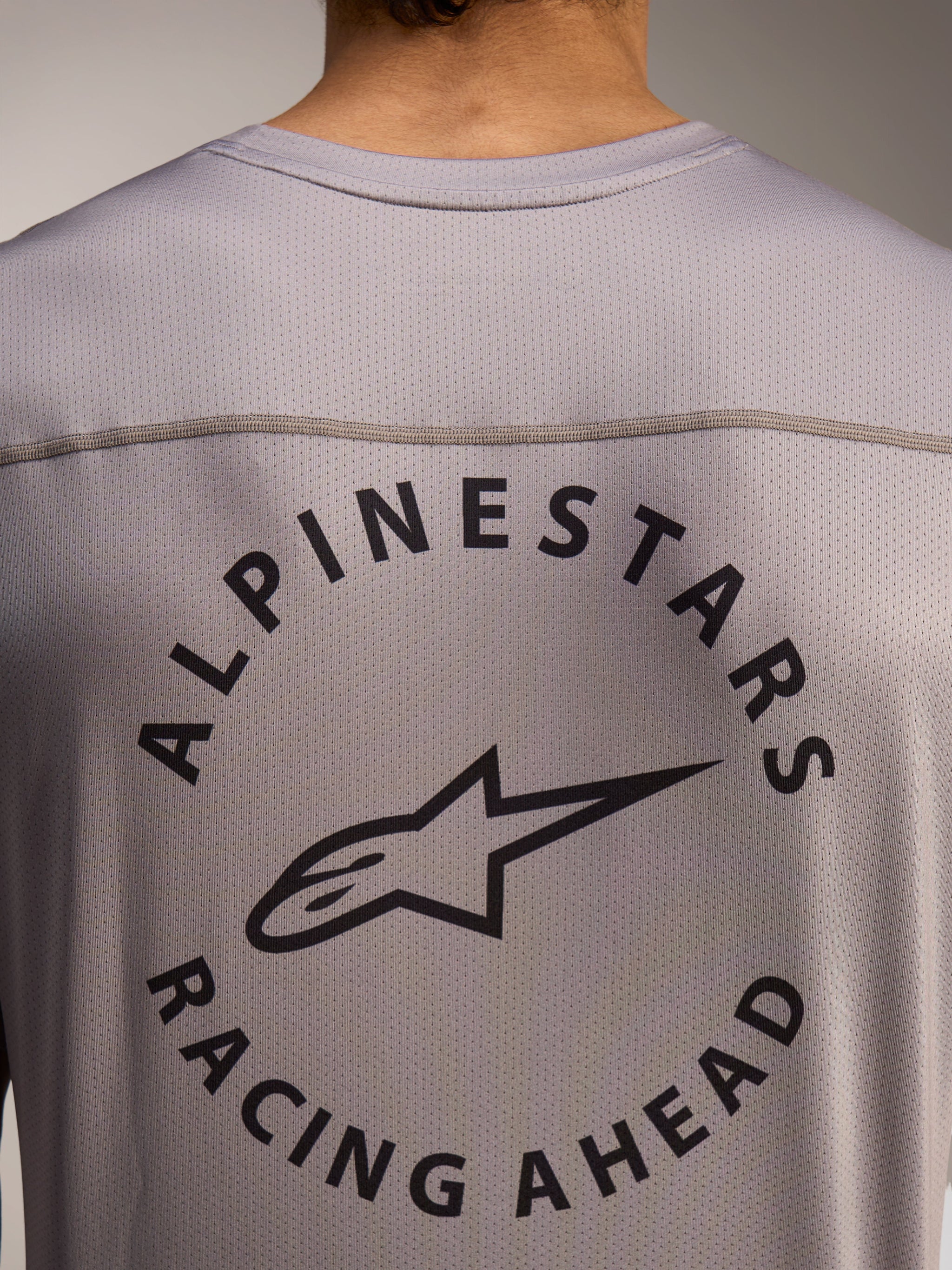 Dettaglio posteriore maglia A-Dura Air grigia con logo Alpinestars Racing Ahead su tessuto mini mesh traspirante.