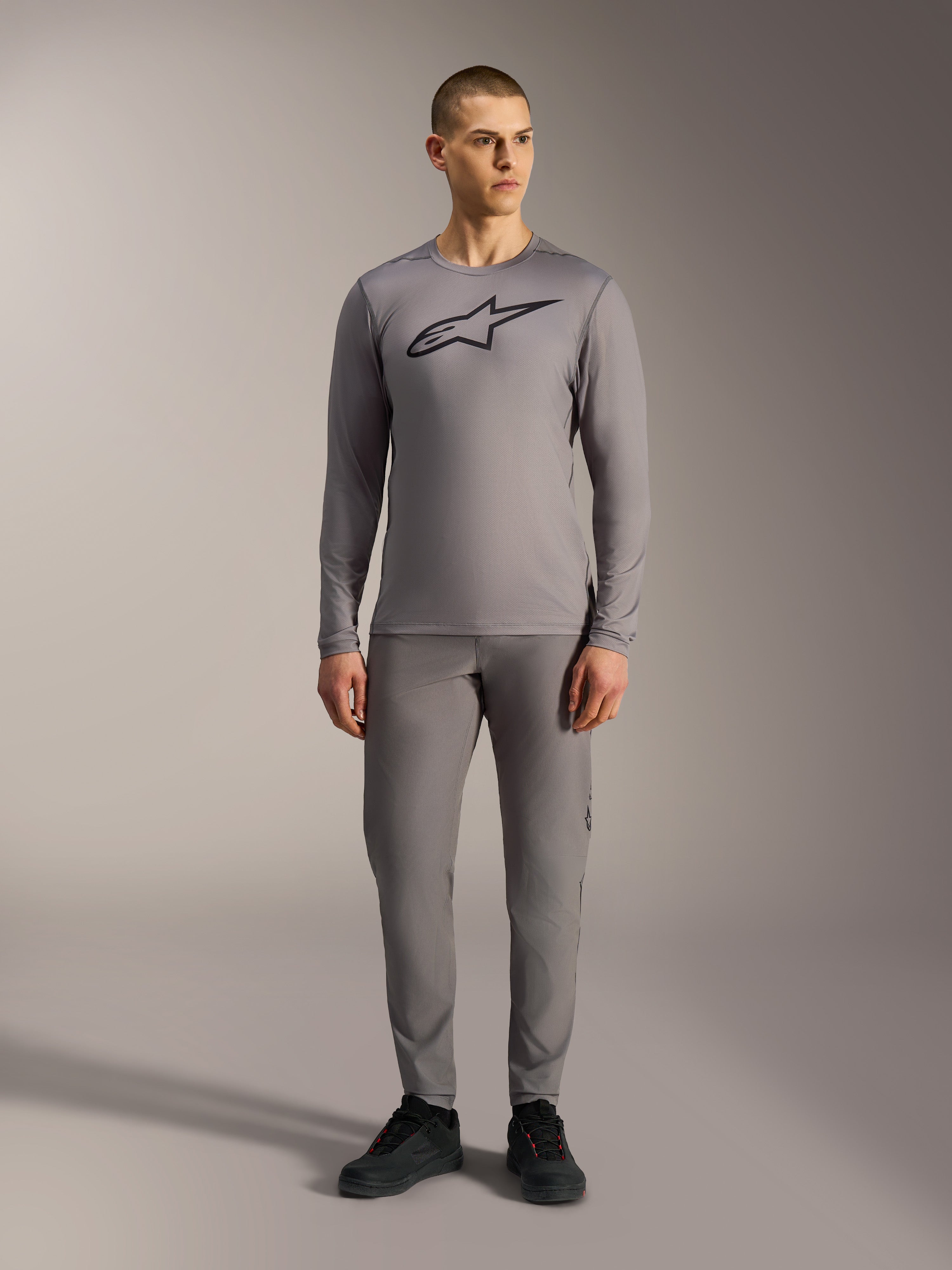Alpinestars A-Dura Ride Maglia maniche lunghe grigia con logo nero sul petto, abbinata a pantaloni MTB coordinati.