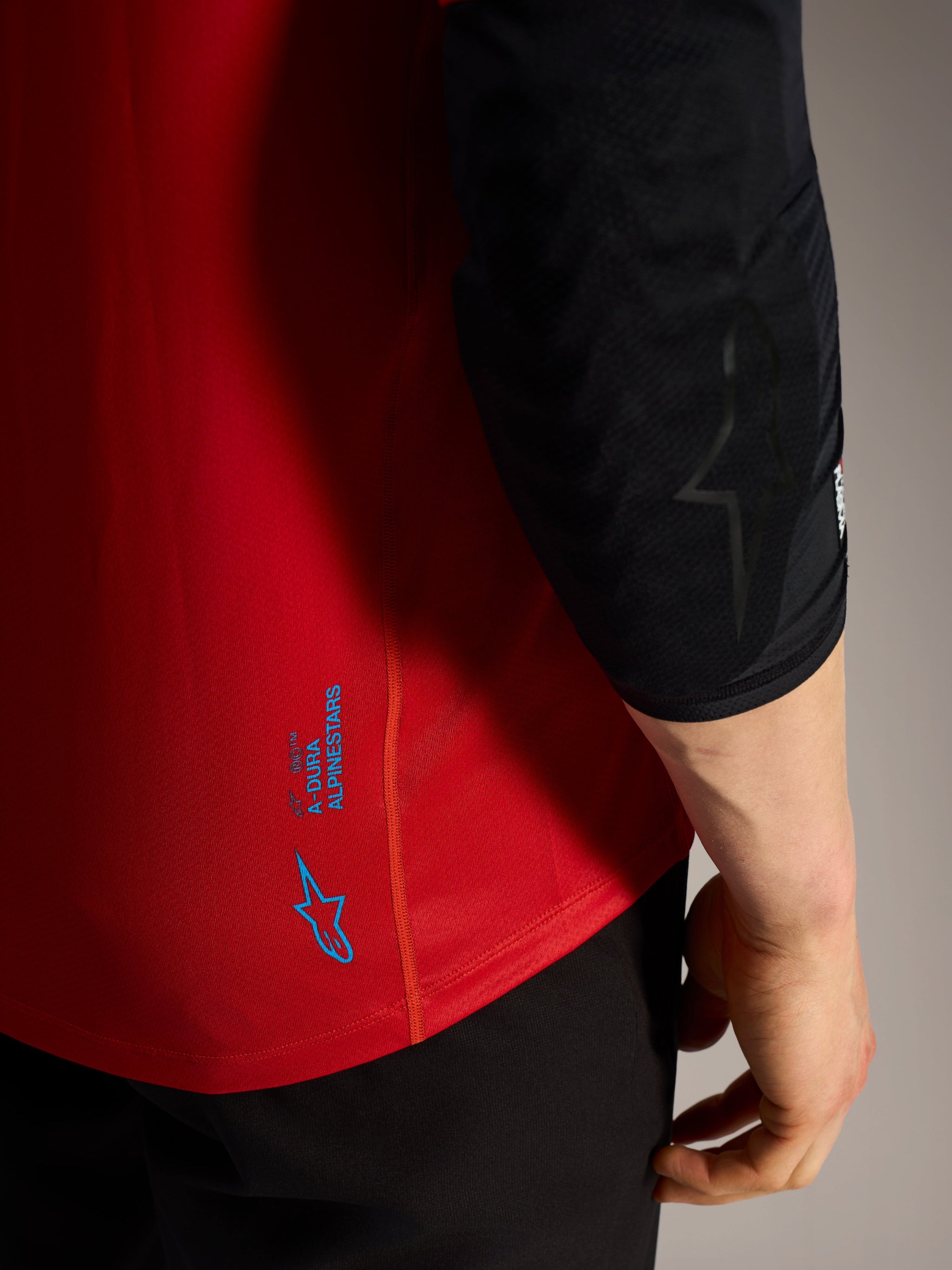 Maglia Alpinestars A-Dura Ride rossa con loghi blu, dettaglio in tessuto tecnico performante da MTB.