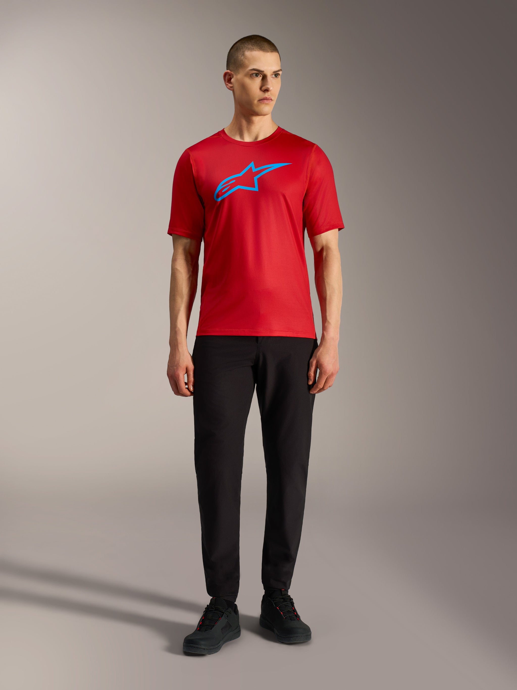 Maglia Alpinestars A-Dura Ride rossa con logo blu, abbinata a pantaloni neri per un look MTB casual.