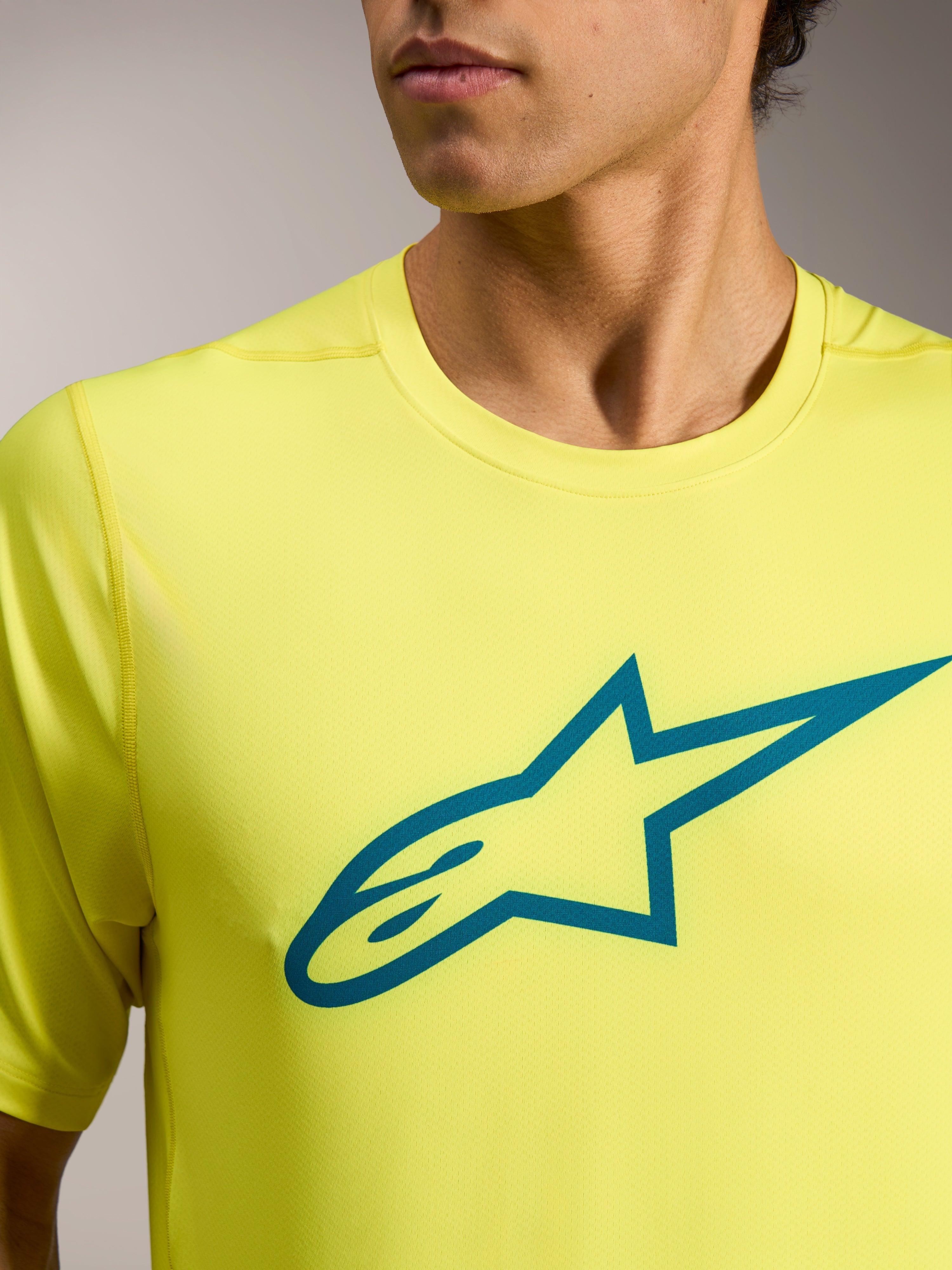 Maglia Alpinestars A-Dura Ride giallo fluo con logo Astars teal sul petto, abbigliamento tecnico leggero da MTB.