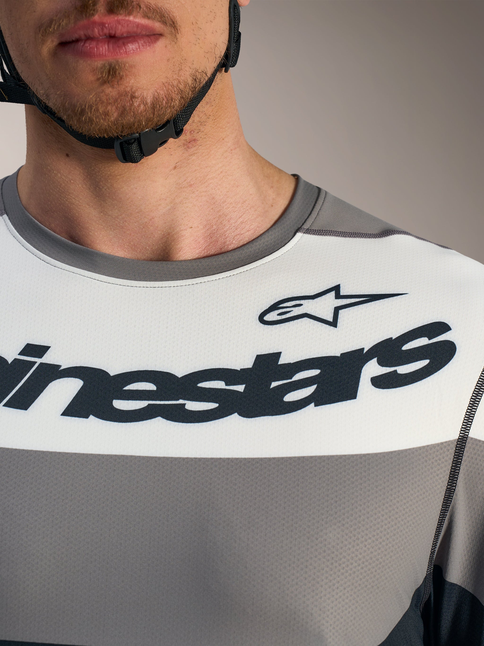 Dettaglio maglia Alpinestars A-Dura Race grigia con pannello bianco e loghi neri sul petto per MTB.