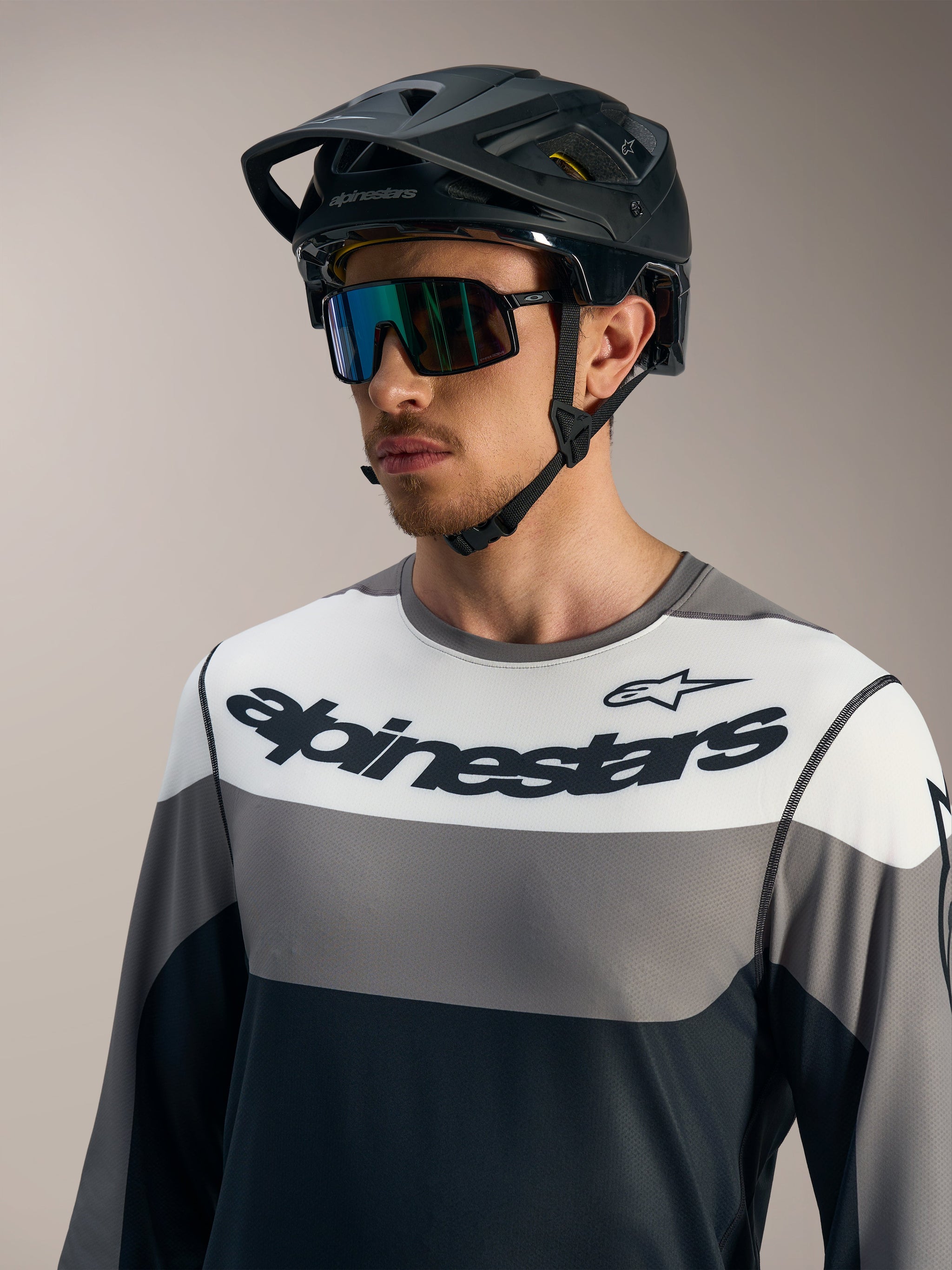 Maglia Alpinestars A-Dura Race a maniche lunghe grigia con pannelli color-block e casco da mountain bike nero.